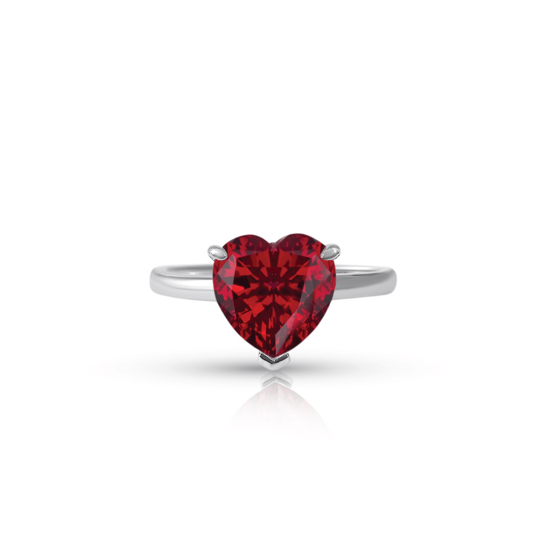 A heart-shaped ring with a red ruby centerpiece and a white gold band.