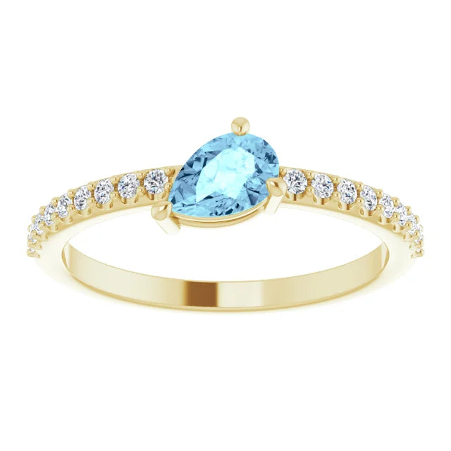 A 14K gold ring featuring a pear-cut aquamarine stone accompanied by round diamonds set in a prong-style band.